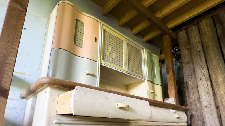 Dalgalı çizgilere sahip, iki çekmeceli, pastel renklerde ahşap tezgahlı vintage mutfak dolabı.