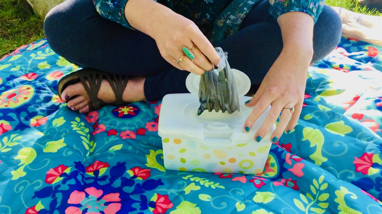 Kadın bebek mendili kutusundan plastik bir poşet çıkarıyor.