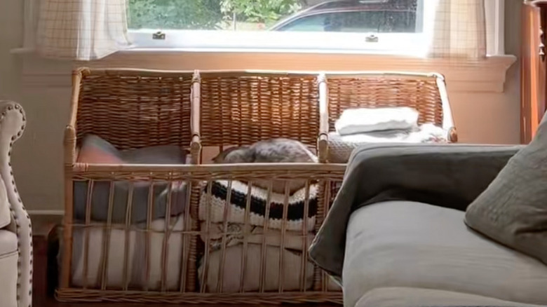 Oturma odasında yedek battaniyelerle dolu kahverengi, vintage bir hasır baget sepeti.