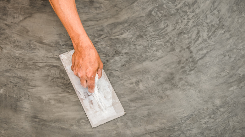 Mala ile tamamlanmış beton levha oluşturan bir el.