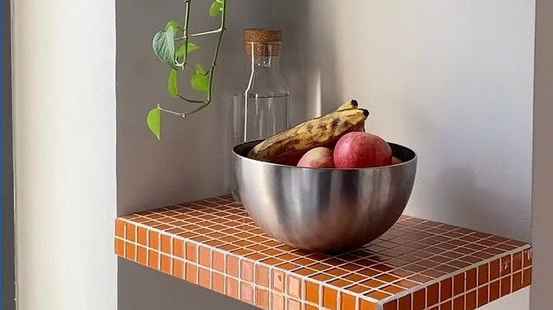 Üzerinde bir kase meyve bulunan seramik raf