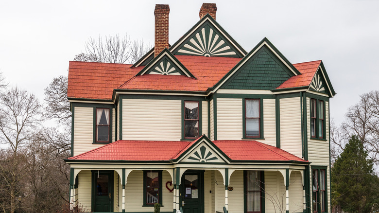 Orman yeşili süslemeli ve pişmiş toprak renkli çatılı, fildişi renginde bir Viktorya dönemi evi