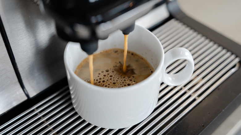 Beyaz bir bardağa espresso döken kahve makinesinin yakın çekimi