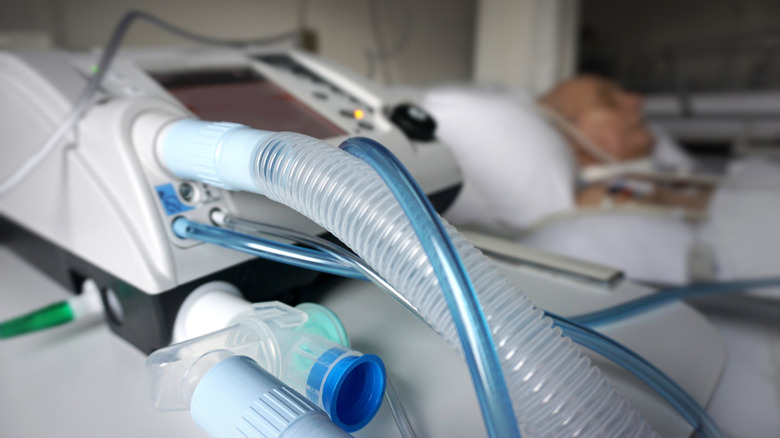 Arka planda entübe hastayla birlikte ventilatör makinesinin kapatılması