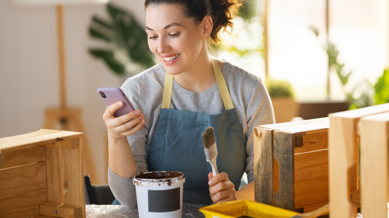 Tahta bir sandığı boyayan kadın