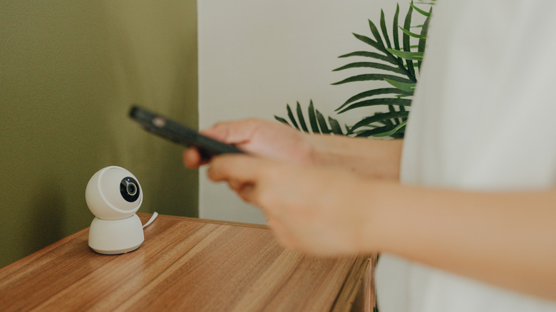 Evde akıllı telefon kontrolü CCTV kullanan kadın eller.