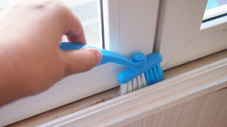 İnce temizleme fırçasıyla kayan rayları temizleyen kişi