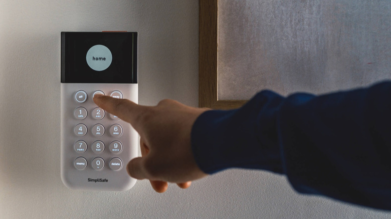 SimpliSafe ana ünitesindeki düğmeye basmak için uzanan el