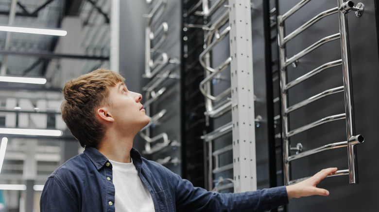 bir adam bir mağazadaki havlu ısıtıcılarına bakıyor