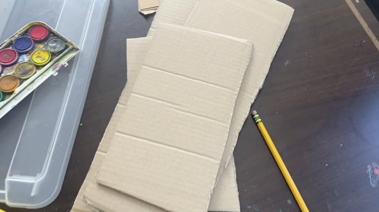 Boyalar ve kalemle sanat masasının üzerinde duran karton parçaları.