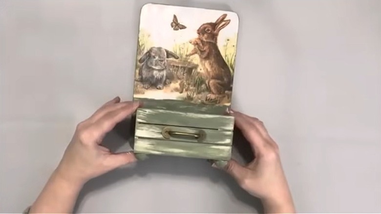 Eller küçük ahşap sandığı sıcak tutkalla süslenmiş kesme tahtasına bastırıyor.