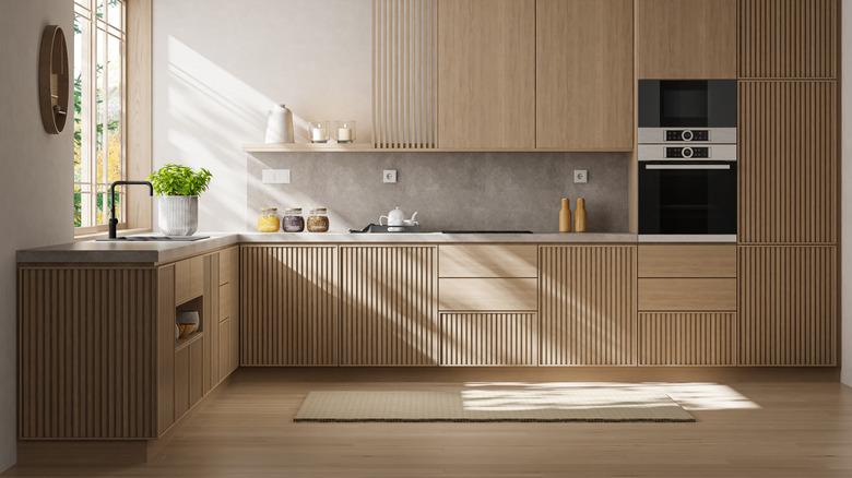 Japonya İskandinav tarzında minimalist mutfak iç mekanı, dikey oluklu mat çam ahşap dolaplar, yumuşak gri tezgah ve temiz, açık bir düzen.