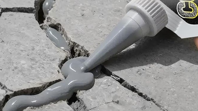 Çatlak bir araba yolu finişerine çatlak dolgusu uygulanıyor