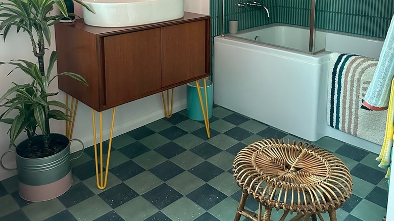 Mavi ve yeşil dama tahtası fayansları ve uyumlu duvarları olan bir banyo