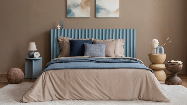 Kahverengi çarşaf ve yastıklar, mavi dekoratif yastıklar, yorgan ve yatak başlığından oluşan çok katmanlı bir yatak