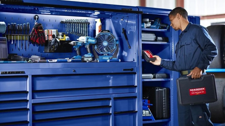 Geniş bir çalışma alanı oluşturmak için döner kabine bağlanan uç dolaptan eşyaları alan kişi