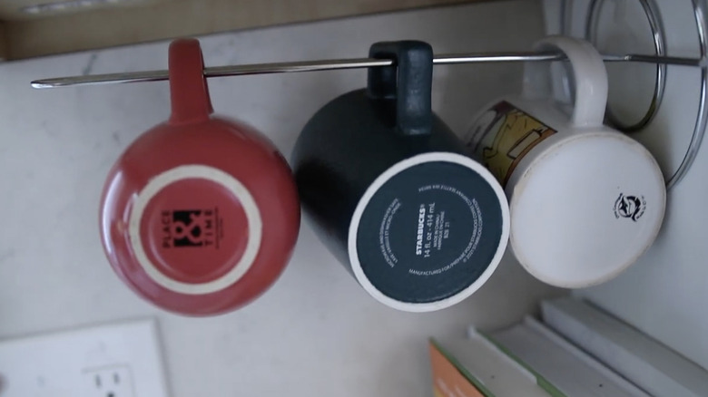 Dikey olarak monte edilmiş bir mutfak rulo tutucusundan sarkan kahve kupaları.