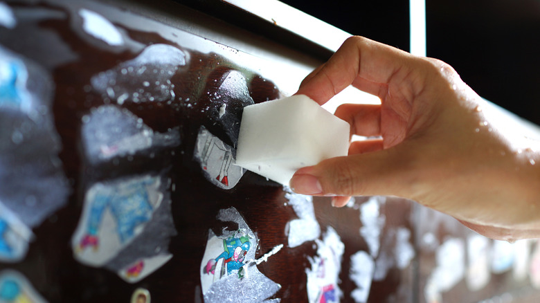 sihirli silgiyle çıkartmaları temizleyen kişi