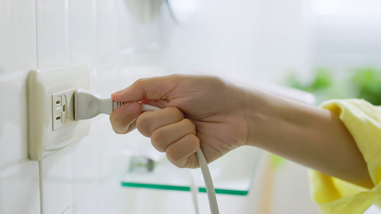 Duvara takılı kabloyu elle tutun