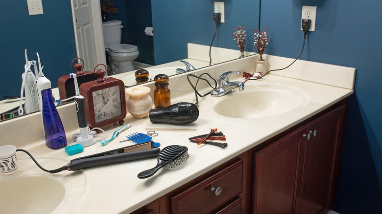Saç kurutma makinesi ve düzleştiricinin takılı olduğu ve tezgahın üzerine bırakıldığı ev banyo makyaj masası