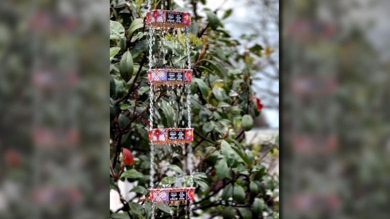 Zincirlerle bağlanan ileri dönüştürülmüş sardalya kutuları yağmur zinciri olarak kullanılıyor.