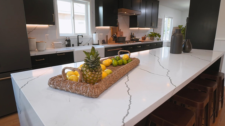 Christina Haack'in mermer tezgah ve koyu kahverengi mutfak dolabının önünde arka panelden oluşan modaya uygun mutfak tasarımı.