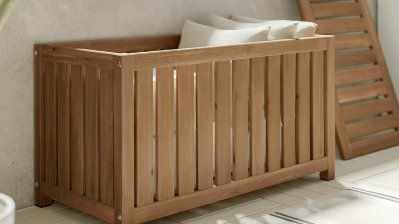 beyaz yastıkların bulunduğu kahverengi IKEA NÄMMARÖ saklama kutusu