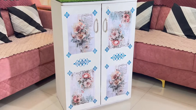 Pembe kanepenin yanındaki karo zeminde kapıları olan beyaz dekupajlı ayakkabı rafı