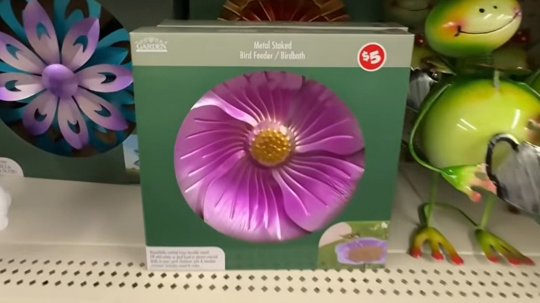 Dolar Ağacı raflarındaki metal kurbağanın yanında 5 dolarlık fiyat etiketi bulunan pembe metal kazıklı kuş besleyici