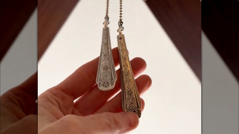 Bir kişi, tavan vantilatörü çekme zincirinin uç parçaları olarak kullanılan kaşık saplarını tutuyor.