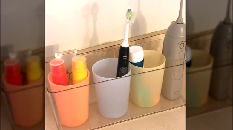 Banyo tezgahında renkli bardaklar halinde düzenlenmiş banyo malzemeleri