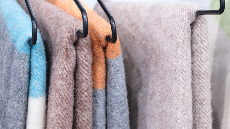 Üst üste elbise askılarında birkaç renkli battaniye.