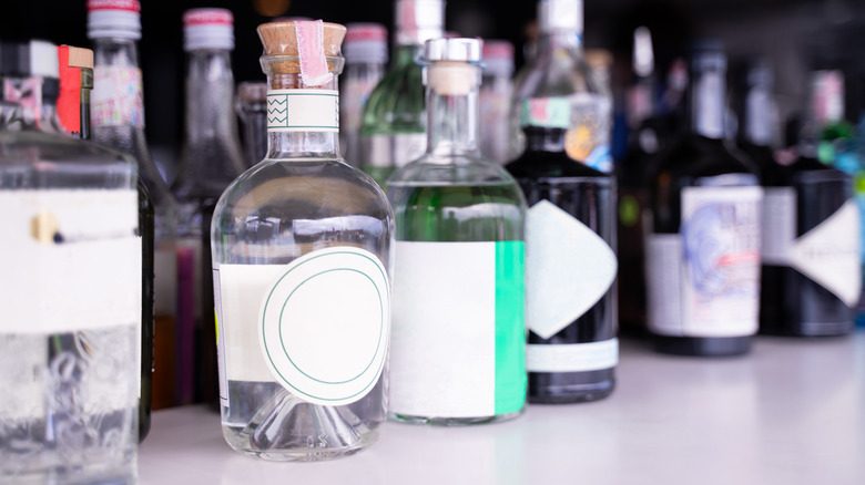 Ön planda berrak likör de dahil olmak üzere dizilmiş cam alkol şişeleri