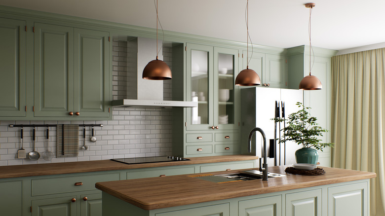 Yeşil dolapları ve bakır sarkıt ışıkları olan modern mutfak
