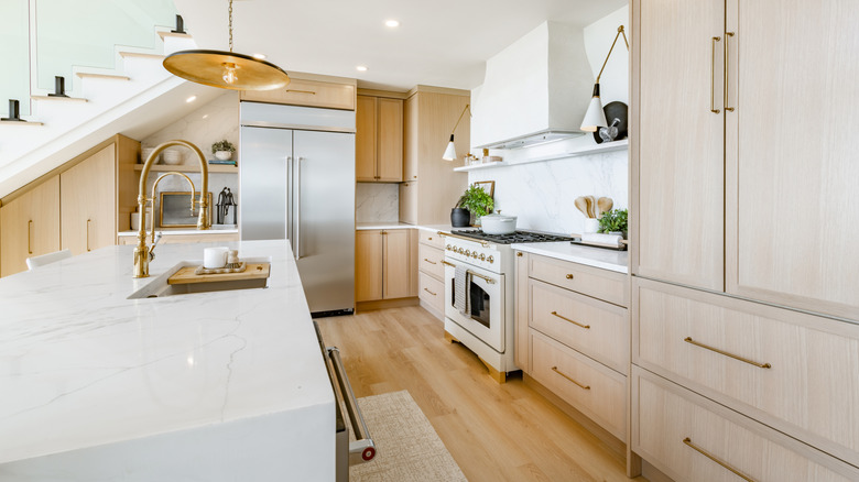 Sıcak beyaz vurgulara ve açık renkli ahşap dolaplara sahip modern mutfak