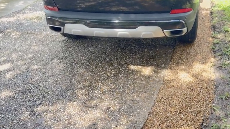 Bir arabanın lastiği dar bir araba yolunun kenarındaki çakıl şeridinin üzerinde duruyor.