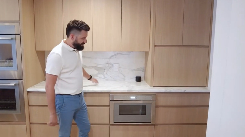 Mermer beyaz backsplash ve beyaz meşe dolaplara sahip mermer beyaz mutfak adası