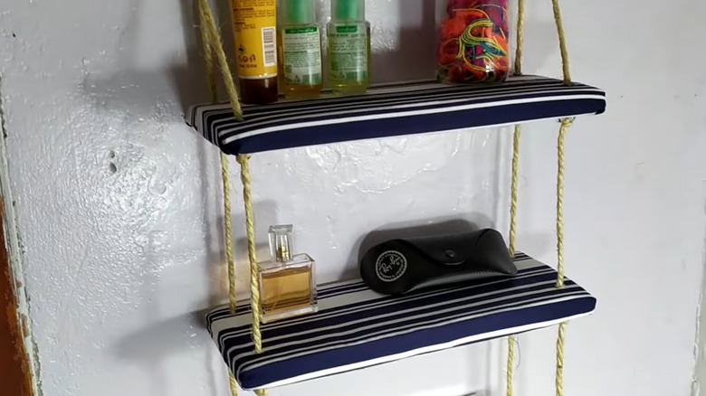 Kartondan yapılmış, kumaşa sarılı, üstünde banyo malzemeleri bulunan raflar