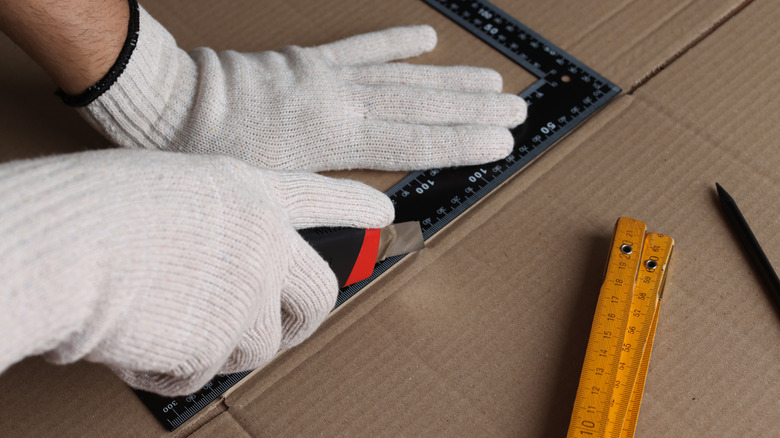 Maket bıçağıyla karton parçalarını kesen bir kişi
