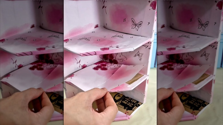 Karton artıklarından yapılmış ve kağıtla süslenmiş bir DIY rafı.