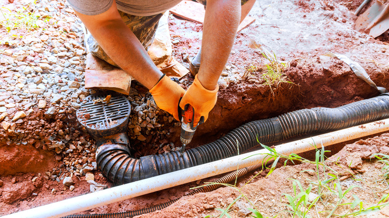 Yüklenici avludaki yer altı borusunu tamir etmeye çalışıyor