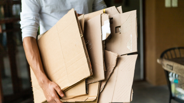 Katlanmış geri dönüştürülmüş karton taşıyan kişi