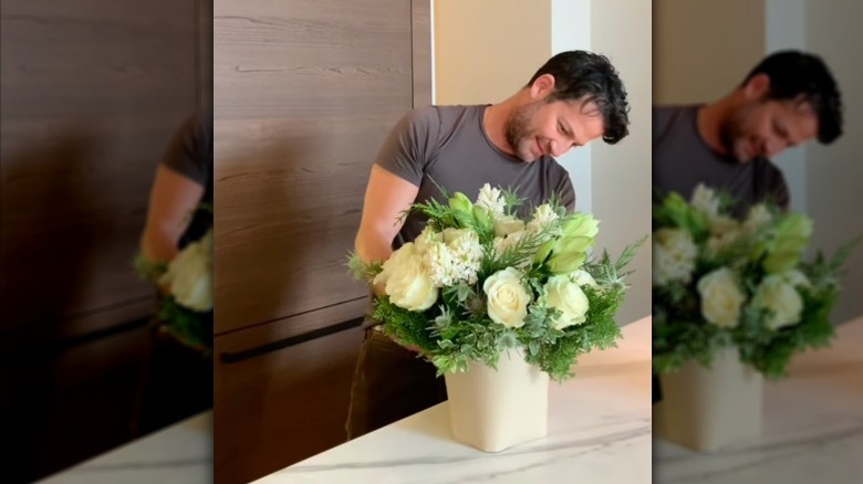 Nate Berkus, mermer mutfak tezgahı üzerinde yeşil ve beyaz bir buket aranjmanı oluşturuyor.