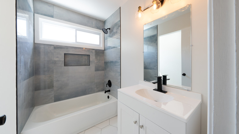 Duşta fayanslar bulunan, tamamen beyaz minimal bir banyo