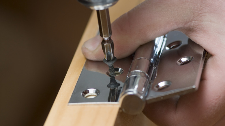 Kapıya menteşe ekleyen birinin yakından görünümü