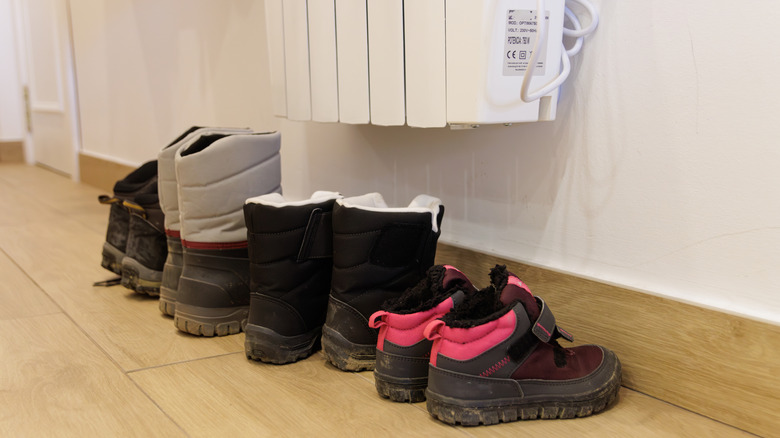 Kuruması için radyatörün altına doğrudan temas etmeyen bir dizi ayakkabı.