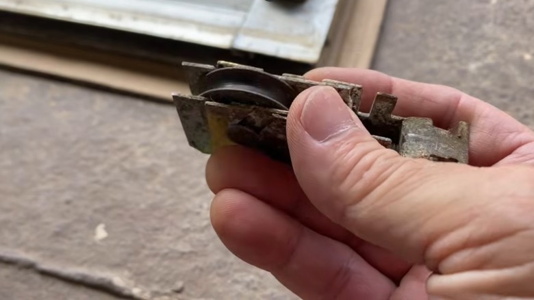 eski, kirli sürgülü cam kapı silindirini tutan adam