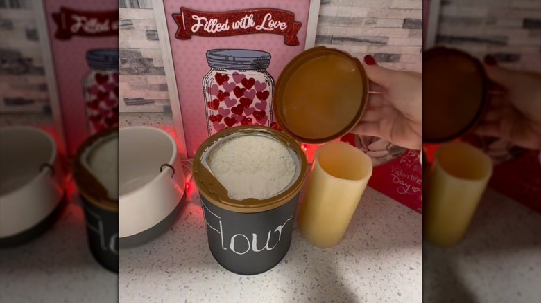 Kadının eli, un kutusuna dönüştürülmüş bir bebek maması kabının kapağını açık tutuyor.