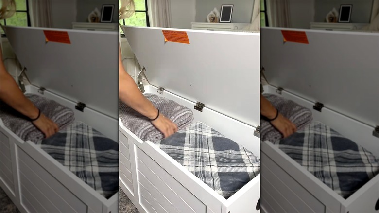 Kadın katlanmış battaniyeleri bagaja yerleştiriyor.