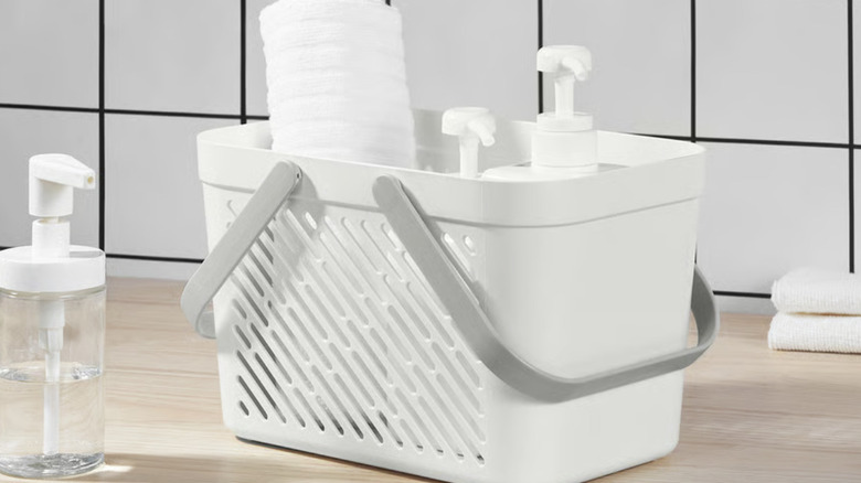 Banyo tezgahı üzerinde IKEA RÅNEN sepet, içinde pompalar ve havlu var